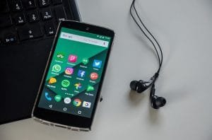 Smartphone ligger på laptop med hörlurar bredvid sig